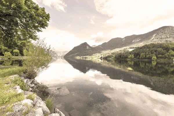 Austrian landscape with forests, meadows, fields and pastures surrounding the lake Grunlsee on the background of Alps. Vintage style