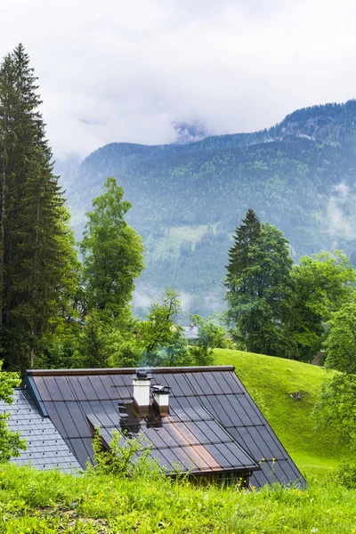 Morning mist over the Austrian landscape with forests, mountains, pastures, meadows and villages.  Rain and clouds over the wet roof in rural Austria