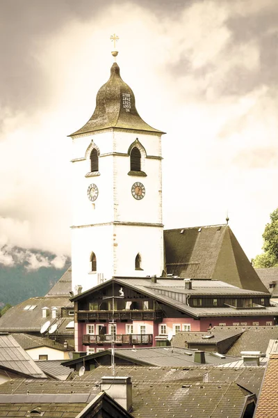 朝圣教堂直接位于奥地利圣沃尔夫冈中心 奥地利中世纪小城市上空的雨 晨雾和云朵 复古风格 — 图库照片