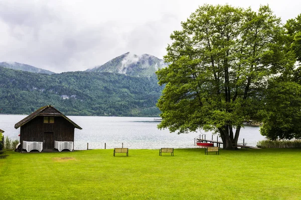 オーストリアのWolfgangseeで雨と朝の霧 オーストリアの田園風景の湖の近くの芝生の上にベンチ付きの小さな手入れの行き届いた公園 ヴィンテージスタイル — ストック写真