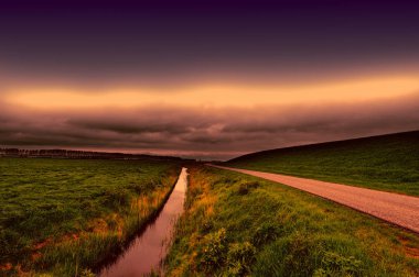 Tarım arazi üzerinden Hollanda'da bkz: günbatımında geri. Asfalt yol boyunca koruyucu baraj ve Hollanda'da kanal