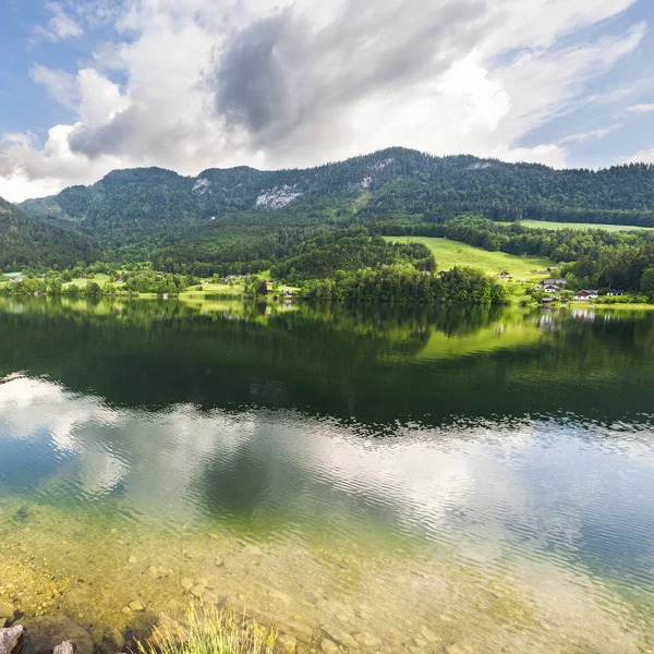 Austrian landscape with forests, meadows, fields and pastures surrounding the lake Grunlsee on the background of Alps