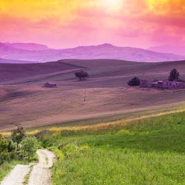Gündoğumunda Sicilya manzarası, tepeler, tarlalar, çiçekler, çayırlar ve güneş ışığı