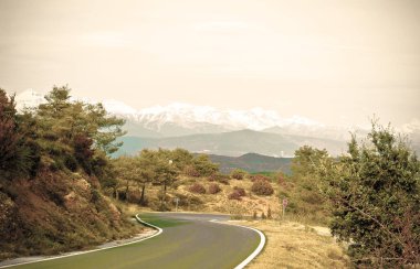İspanya 'daki karlı Pireneler' in arka planında asfalt yol var. Klasik stil