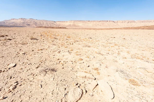 이스라엘 사막에 암석층의 소름끼치는 디스와 분화구들이 먼지투성이의 산들을 가로막고 — 스톡 사진