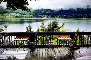 Avusturya 'da Wolfgangsee Gölü' ndeki açık hava kafe. Sabah sisi, yağmur ve bulutlar Avusturya topraklarında göl, ormanlar, tarlalar, otlaklar, çayırlar ve köyle birlikte. Klasik stil