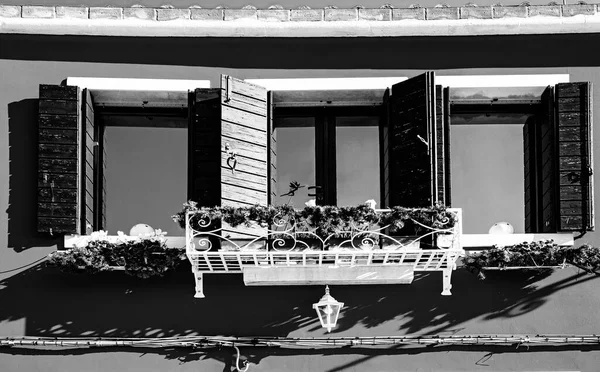 Italian culture on Venetian facades in black and white. Venice is rich and poor, well-groomed and abandoned, reflected in its windows.