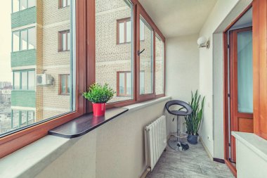 Küçük, temiz bir balkon. Minik apartman dairesinde camları olan bitkiler.