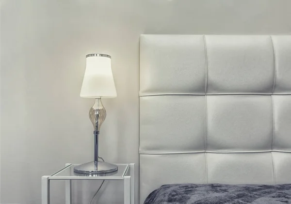 Warm cozy lamp near bed and headboard on night stand