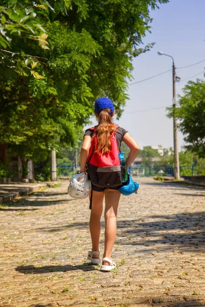 little girl athlete goes to martial arts training on an empty street with a backpack with equipment