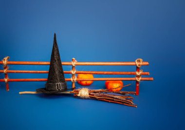 Balkabağıyla çitin yanında uçmak için klasik bir cadı şapkası ve süpürgesi.