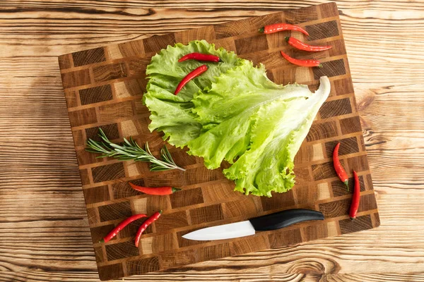 Rosso, maturo, insalata brillante e peperoni si trovano su un tagliere di legno vicino al coltello da cucina . — Foto Stock