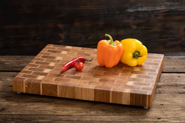 I peperoni maturi, lucenti si trovano su un tagliere di legno . — Foto Stock