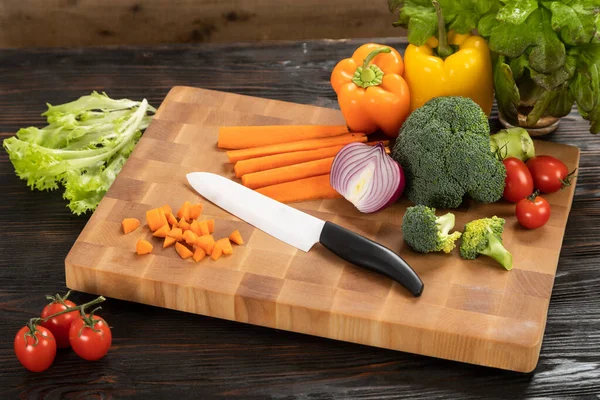 Verduras y cuchillo en una tabla de cortar de madera — Foto de Stock