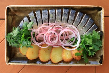 Plaka üzerinde patates dilimleri ile marine edilmiş ringa balığı