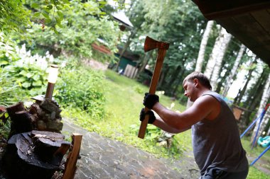 Adam kesme ahşap günlükleri ile arka bahçede balta