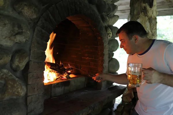 ビールのグラスを持つ人 Kindle 暖炉の火 — ストック写真