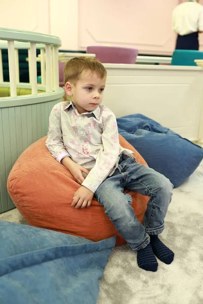 沉思的孩子坐在豆袋椅子上 — 图库照片