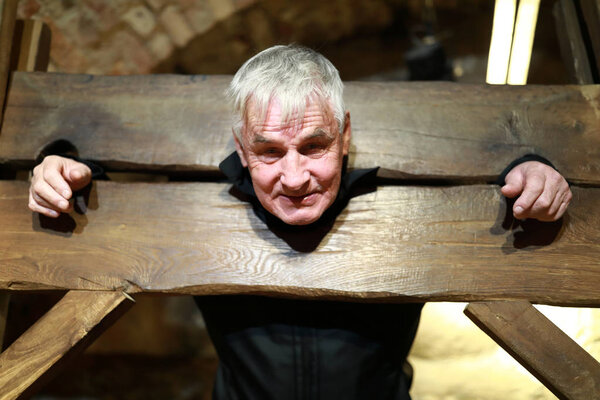 Portrait of elderly man in a wooden pillory