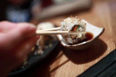 Kişi suşi restoranında soya soslu dips