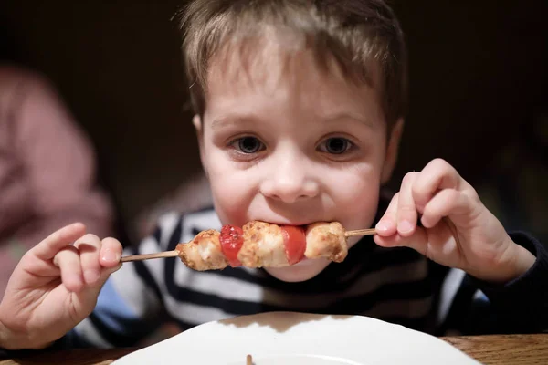 レストランで串焼きのケバブを食べる少年 — ストック写真