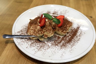 Tiramisu beyaz plaka üzerinde çilek dilimleri ile