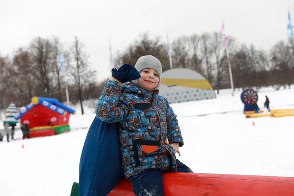 冬の遊び場でログの上にバッグを持つ子供 — ストック写真
