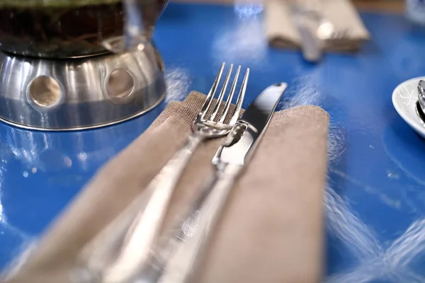 青いテーブルの上のナプキンにフォークとナイフ — ストック写真