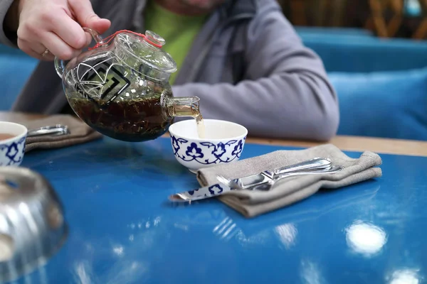 Person pours tea into cup in restaurant