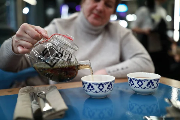 女性がレストランでカップに紅茶を注ぐ — ストック写真