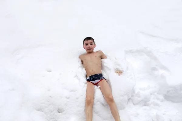 Criança nua deitada na neve — Fotografia de Stock