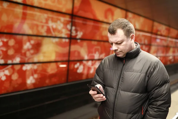 Человек со смартфоном ждет поезд — стоковое фото