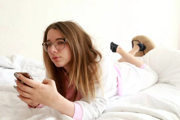 Tiener met smartphone liggend op bed — Stockfoto