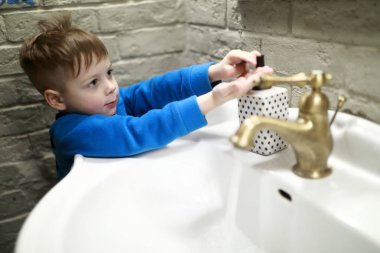 Çocuk ellerini yıkıyor.