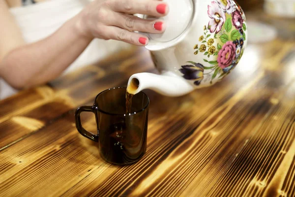 Woman pouring tea from ceramic teapot — Stock Photo, Image