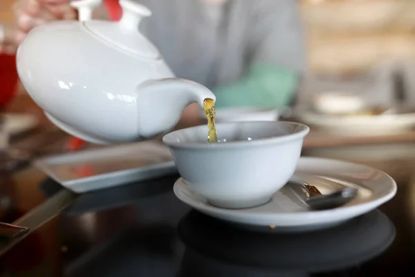 Person som häller te från vit tekanna — Stockfoto