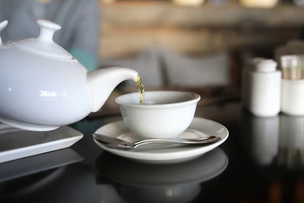 Person pours tea from white teapot — Stock Photo, Image