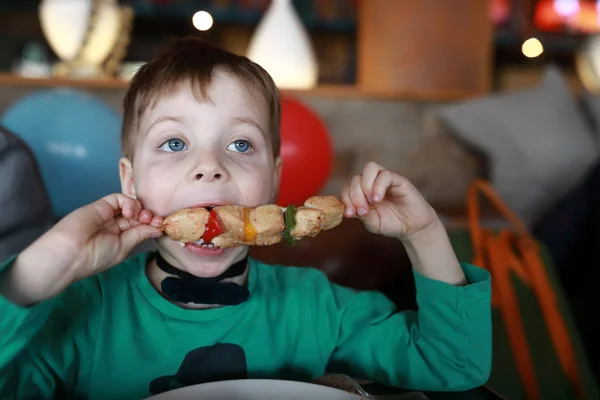 Мальчик ест кебаб на шампуре — стоковое фото