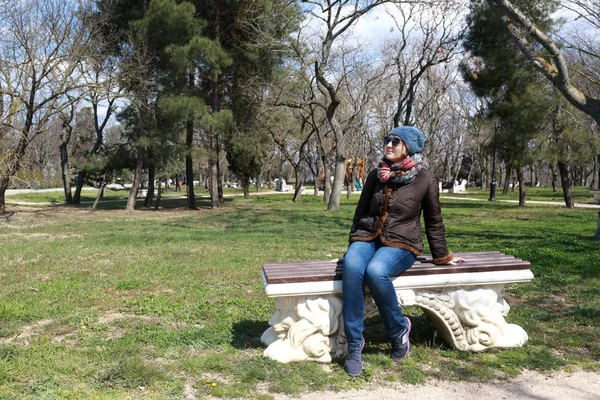 Žena sedí na lavičce na jaře — Stock fotografie