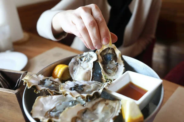 Person squeezes lemon juice on oysters — Stock Photo, Image