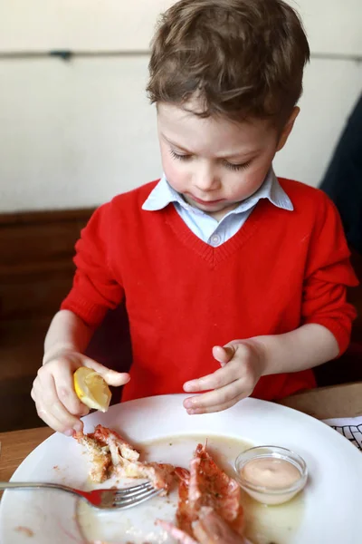 子供はエビにレモンジュースを絞ります — ストック写真