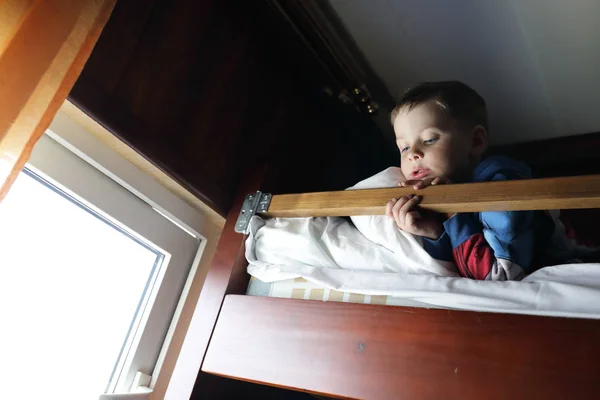 Boy on bed in cabin of ship — Stock Photo, Image