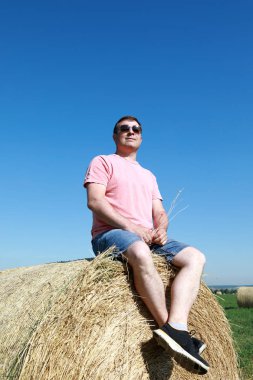 Saman balyası üzerinde oturan turist