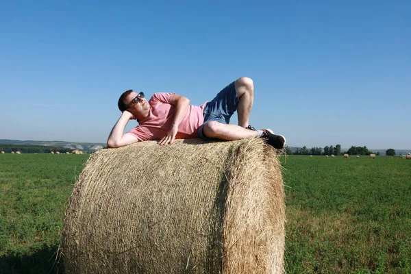 Man lying on bale of straw — Stock Photo, Image