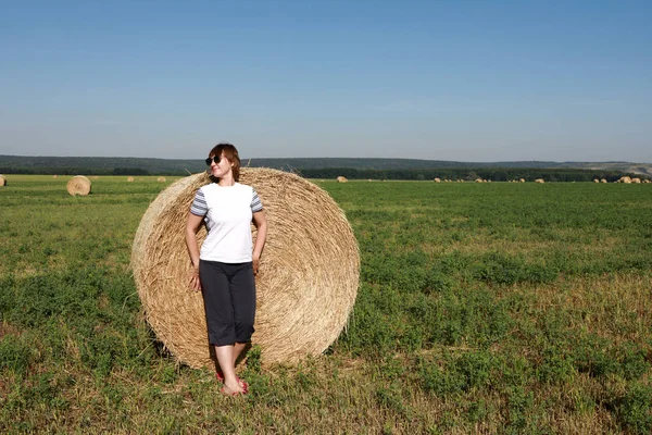 Woman standing next to bales of straw — Stock Photo, Image