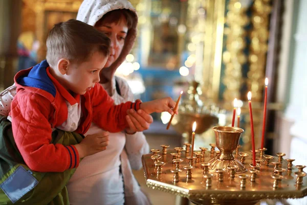 Mor med son sätta ljus i kyrkan — Stockfoto