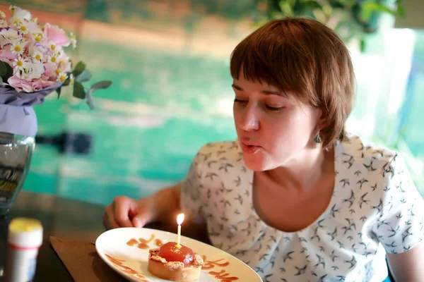 Woman blows out candle on cake — Stock Photo, Image