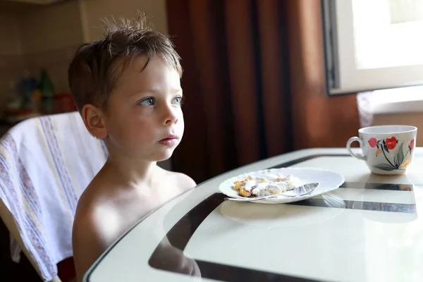 Pojke äter cheesecakes till frukost — Stockfoto