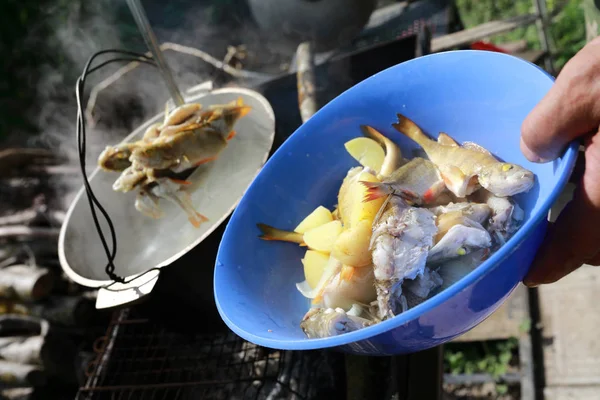 Man takes fish out of soup — Stock Photo, Image