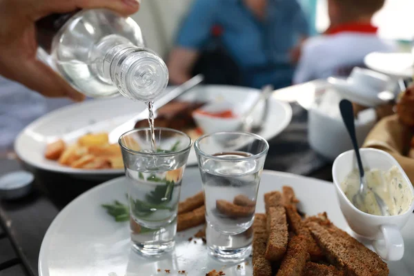 Garçom derramando vodka em copos — Fotografia de Stock